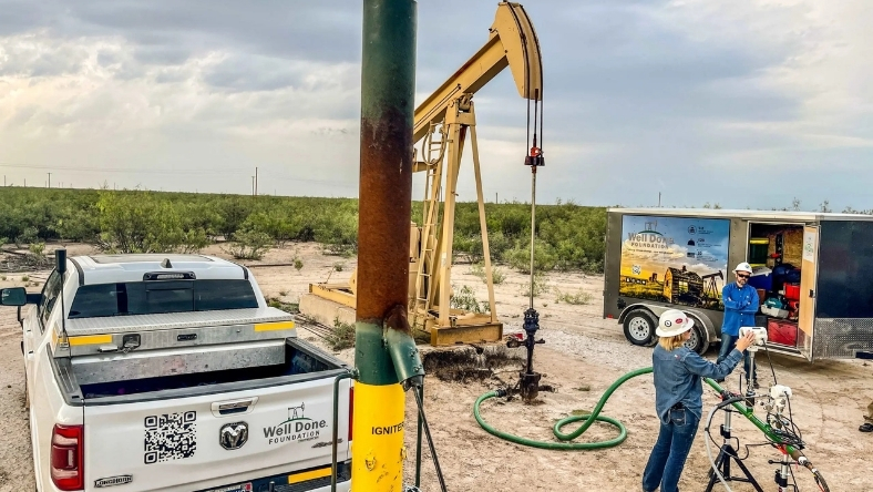 Workers conducting onshore oil well remediation using service equipment