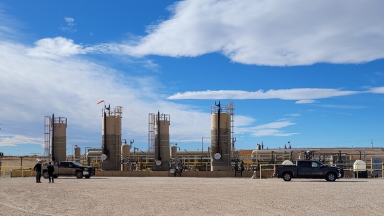Oil and gas wellsite with processing equipment and vehicles in open terrain